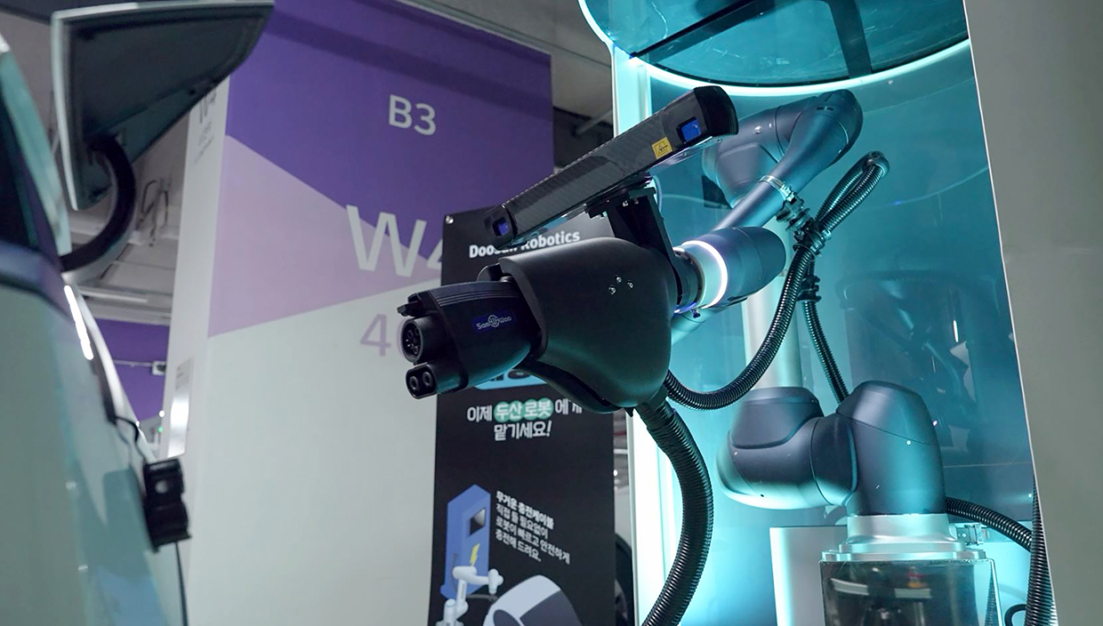 ▲ A collaborative robot is adjusting its position to connect the charger cable to the electric vehicle's charging port.